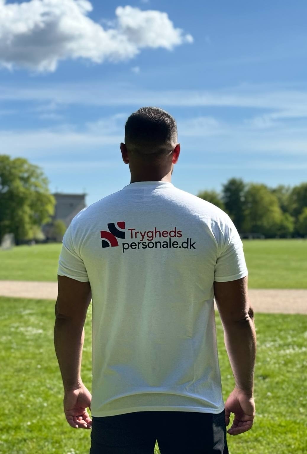Tryghedspersonale medarbejder med logo på ryggen i park miljø - professionel støtte